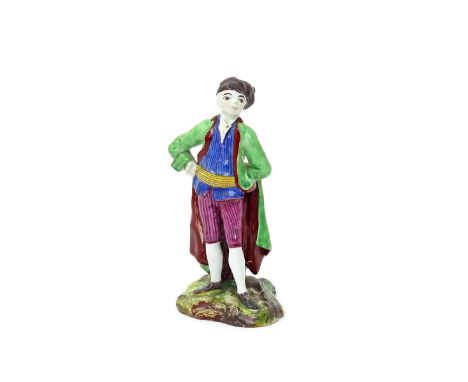 A Höchst faïence figure of a gentleman c.1760, possibly from the Commedia dell'Arte, wearing a long green coat and a striped 