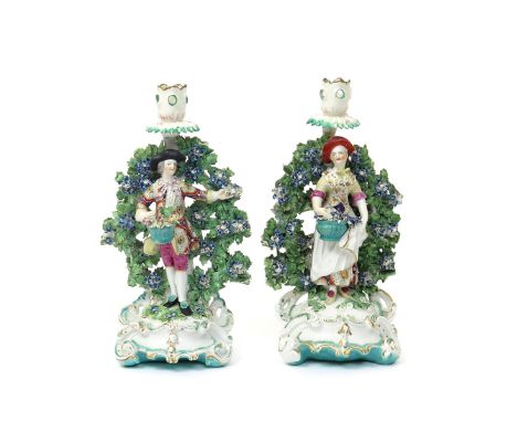 A pair of Derby candlestick figures of gardeners  c.1765, the gentleman holding a basket of apples, the lady a basket of flow