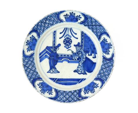 A Delft plate  c.1700, painted with a Chinese gentleman and a young maiden in an interior beneath a large lamp, the rim with 