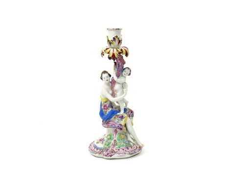 A Bow candlestick figure  c.1760-65, emblematic of Summer, modelled as Ceres seated on a stump and supporting a putto on her 