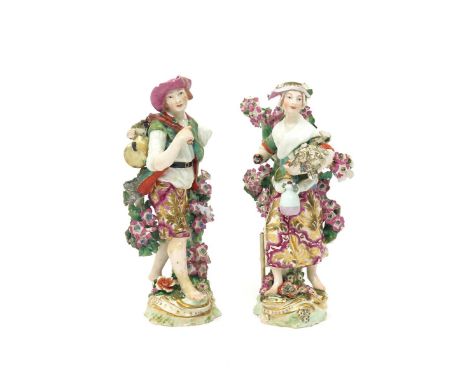 A pair of Chelsea figures of harvesters  c.1765, he carrying a keg on a stick slung over one shoulder, she with a sheaf of co