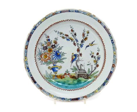 A Milan faïence plate  c.1760-80, painted with a large bird perched on the trunk of a flowering tree, another in flight besid