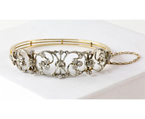 An early 20th century openwork diamond bangle, old cut diamonds set in tested platinum, with central old cut diamond measurin
