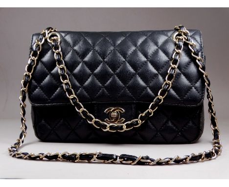 A black leather fashion bag - of quilted design with a leather and gilt chain intertwined shoulder strap.