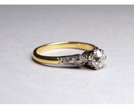 A solitaire diamond ring set in an 18ct yellow gold band - the claw set stone with diamond set shoulders, ring size M, weight