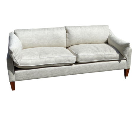 A beige upholstered sofa with cream piping detail - raised on wooden feet with white metal detail, height 81cm, width 206cm, 