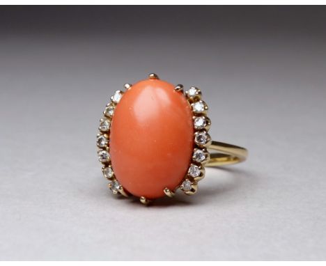 An 18ct yellow gold coral and diamond dress ring - the cabochon polished oval stone flanked by diamonds, size N, weight 6g.