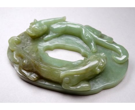 A jade tsuba - modelled with a pair of dragons, the reverse carved with foliage, height 10cm.