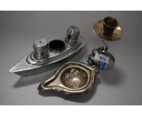 A mid century New Zealand paua shell candlestick, a plated strainer and a vintage novelty ship shaped cruet.