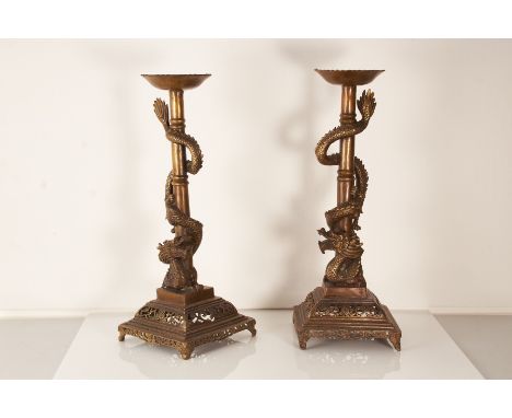 A pair of 20th century Chinese base metal candle standsThe pierced stepped square bases on bracket feet with a central column