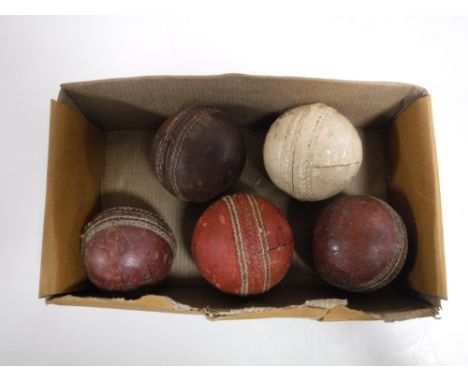 A box containing five vintage cricket balls