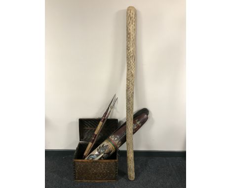 A wicker dome topped box containing two tribal spears, two wall masks and rain stick