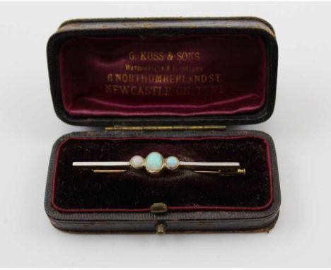 AN OPAL SET BAR BROOCH, the plain yellow metal bar set central oval cabochon fiery opal flanked by two circular ones, 5cm lon