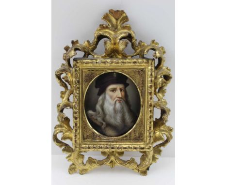 A HAND PAINTED PORCELAIN PANEL DEPICTING A SELF PORTRAIT AFTER LEONARDO DA VINCI, mounted within a gilded, carved wood floren