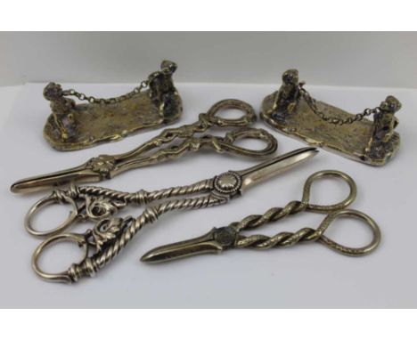 A PAIR OF SILVER PLATED KNIFE RESTS, modelled as a pair of dogs, united by a chain on ground work bases, 9cm x 4cm, together 