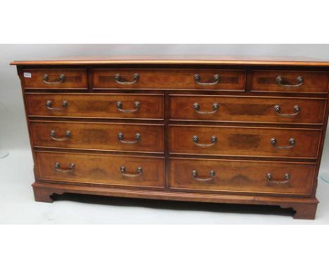 A WELL MADE REPRODUCTION DOUBLE WIDTH CHEST having crossbanded top, over three inline drawers and three further banks of twin