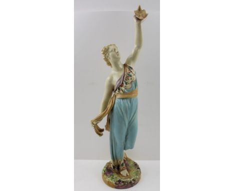 A ROYAL WORCESTER CERAMIC FIGURE, depicting a classically robed woman holding a bird aloft in her left hand, on ground work b