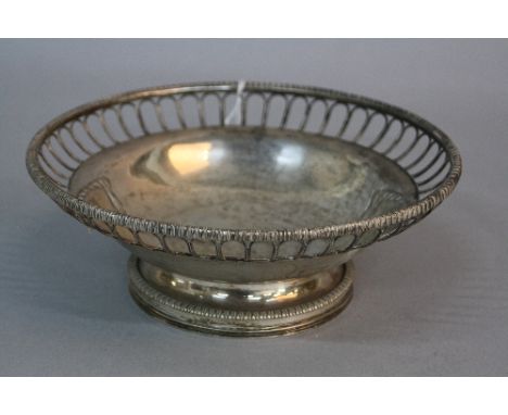 A GEORGE V CIRCULAR SILVER FRUIT BOWL, gadrooned rim, arched design open wire border, the centre engraved with monogram, step