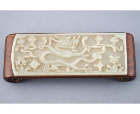 A carved jade and wood brush stand of rectangular form, the jade panel relief carved with a dragon in foliage, set into a har