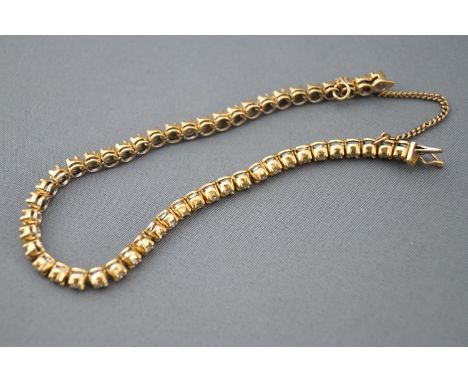 A yellow metal diamond line bracelet. Set with fifty round brilliant cut diamonds. Estimated total weight of 1.00cts. Colour: