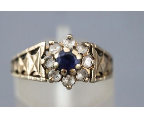 A yellow metal cluster ring set with blue and white sapphires (stones untested). Hallmarked 9ct gold, London, 1975. Size: K 3