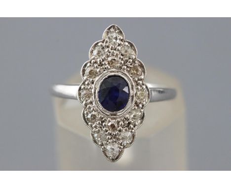 A white metal dress ring set with an oval faceted cut blue sapphire and old cut diamonds. No hallmark - tests indicate 18ct g