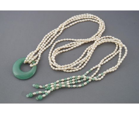 A multi strand freshwater rice pearl necklace with interspaced green beads and large polished green stone pendant. 99.5 grams