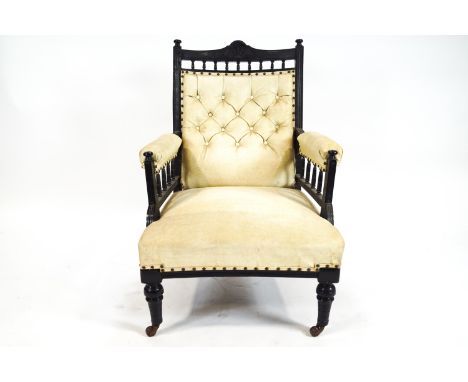 A late Victorian armchair with ebonised frame, leatherette button back seat with padded arms on turned legs and ceramic caste