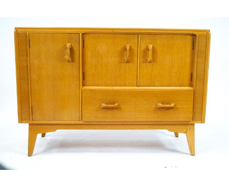 A G-Plan sideboard, in light oak, of plain rectangular form, set a tall cupboard, a two door drinks cupboard and a long drawe
