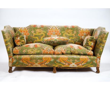 A three seater sofa with raised crested back and arms set with two base and three back cushions, the whole raised on six carv