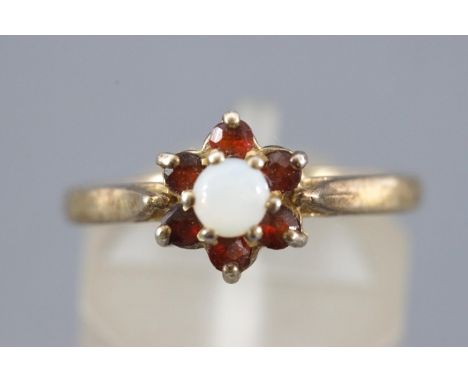 A yellow metal cluster ring set with garnets and opal. Stamped Silver &amp; GP. Size: N 2.0 grams