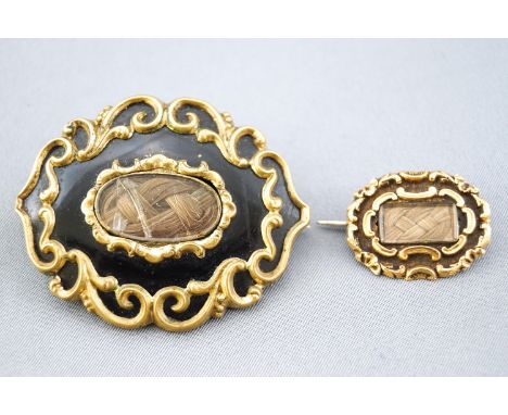 A collection of two Georgian mourning brooches. Scroll design with enamel finish and encased plaited hair. Pin and hook fitti