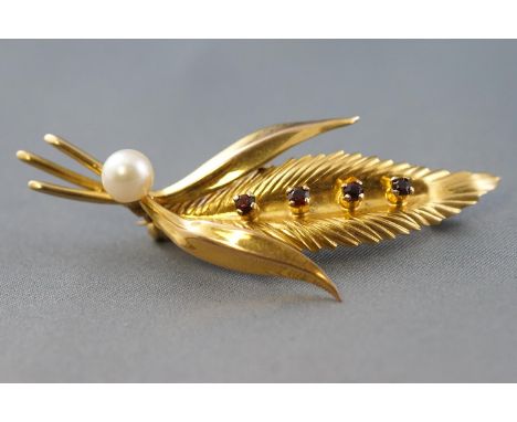A yellow metal leaf brooch set with four round garnets and finished with a cultured pearl. Pin and revolver fittings. Stamped