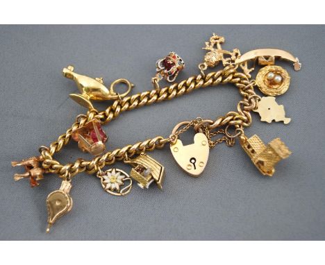 A yellow metal curb link bracelet with assorted charms. Padlock and safety chain. Stamped 9ct with personal inscription. 31.7