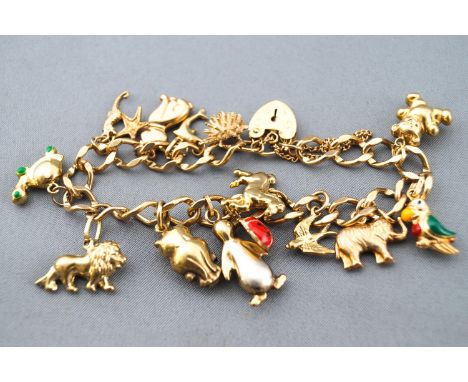 A yellow metal curb link bracelet with assorted charms. Padlock and safety chain. Hallmarked 9ct gold. 21.8 grams