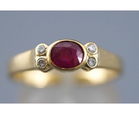 A yellow metal dress ring set with an oval faceted cut ruby and four round cut diamonds. Stamped 18K 750. Size P 4.2 grams