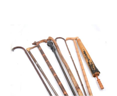 Collection of walking sticks including one carved with a dog's head, African head stick, others and a parasol.