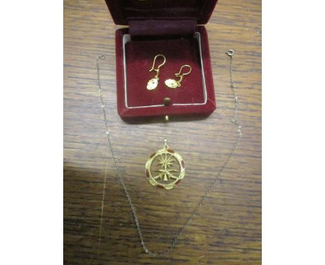 A yellow metal pendant of circular shape with an openwork design of two crossed-swords intersecting with a palm tree, the emb