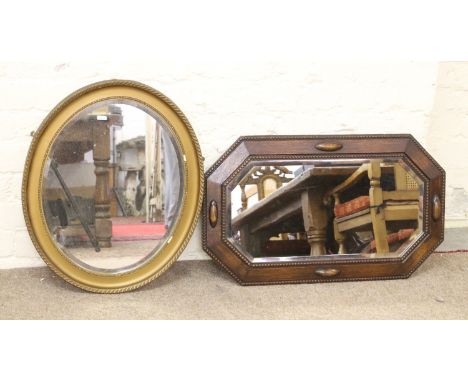 An oval gilt framed bevel edge wall mirror and an oak framed example.