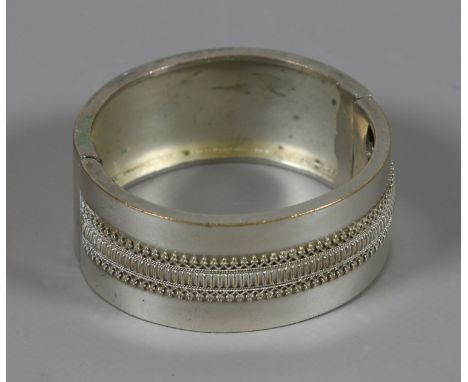 A Victorian silver bangle with applied decorative design.