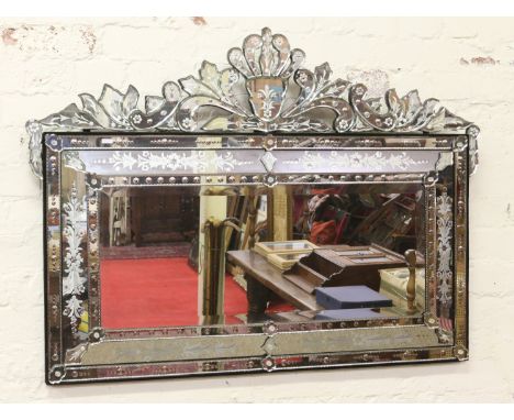 A Venetian bevel edged wall mirror with decorative etched bands of flowers and shaped pediment.