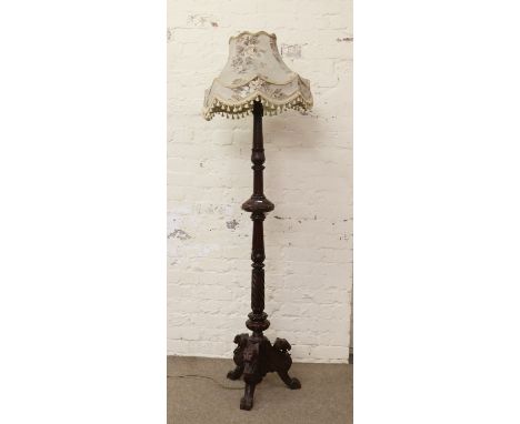 A standard lamp and shade raised on a tripod base mounted with lion mask.