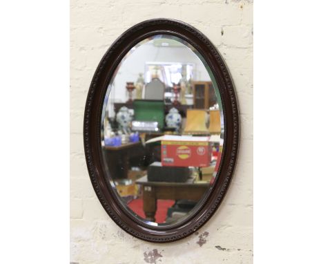 A carved mahogany bevel edge oval wall mirror.