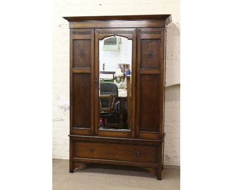 A carved oak mirror front wardrobe with base drawer.