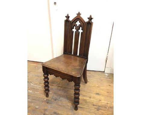 A Victorian Gothic Revival oak hall chair with pierced splat over a solid seat, on bobbin turned front supports (split to sea