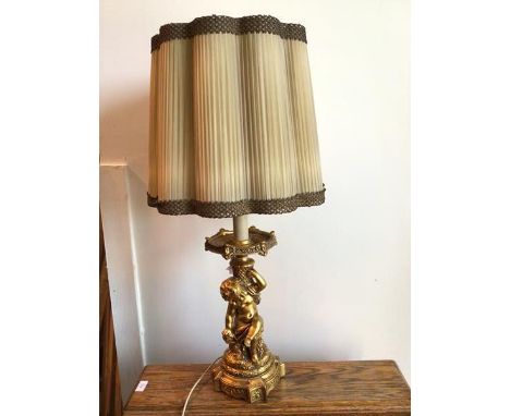 A modern gilt composition table lamp with faux drip tray and seated putti on column base, complete with ruffled shade (to top