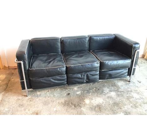 A modernist Grand Comfort three seater sofa in black leather on tubular frame (70cm x 174cm x 71cm)