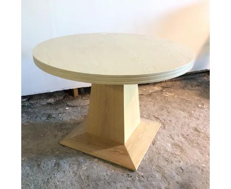 A modern light oak breakfast table, the circular top with chanelled edges, on tapering support, on chamfered base (77cm x 110