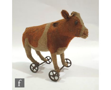 An early 20th Century Steiff cow or ox on wheels, Article No. 1322, circa 1910, brown and white mohair, black boot button eye