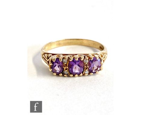 A 9ct hallmarked amethyst three stone ring, stones spaced by two pairs of diamonds, weight 2.7g, ring size O. 